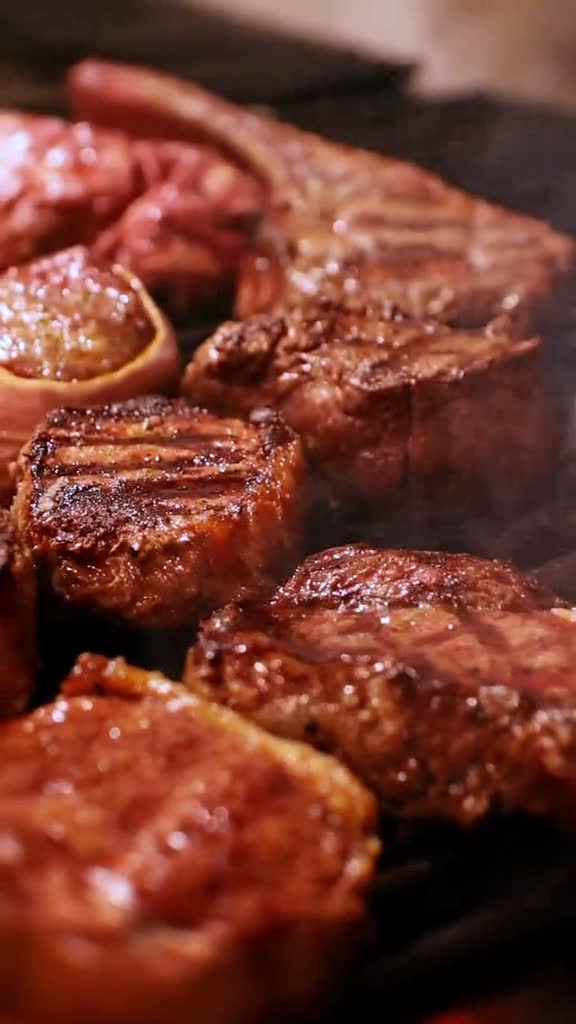 Cortes de carne sobre la parrilla, con humo.